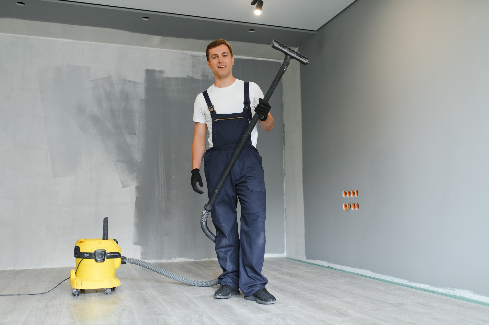 A worker vacuums a room after repairing the floors. Apartment after renovation with a vacuum cleaner